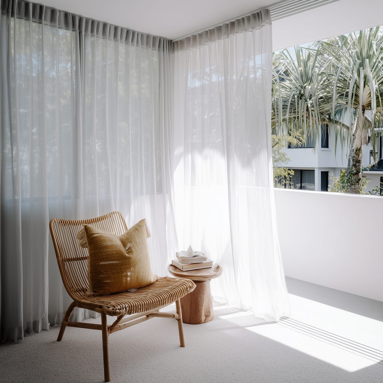 Sheer white curtains on a bright balcony with rattan chair — Byron Bay