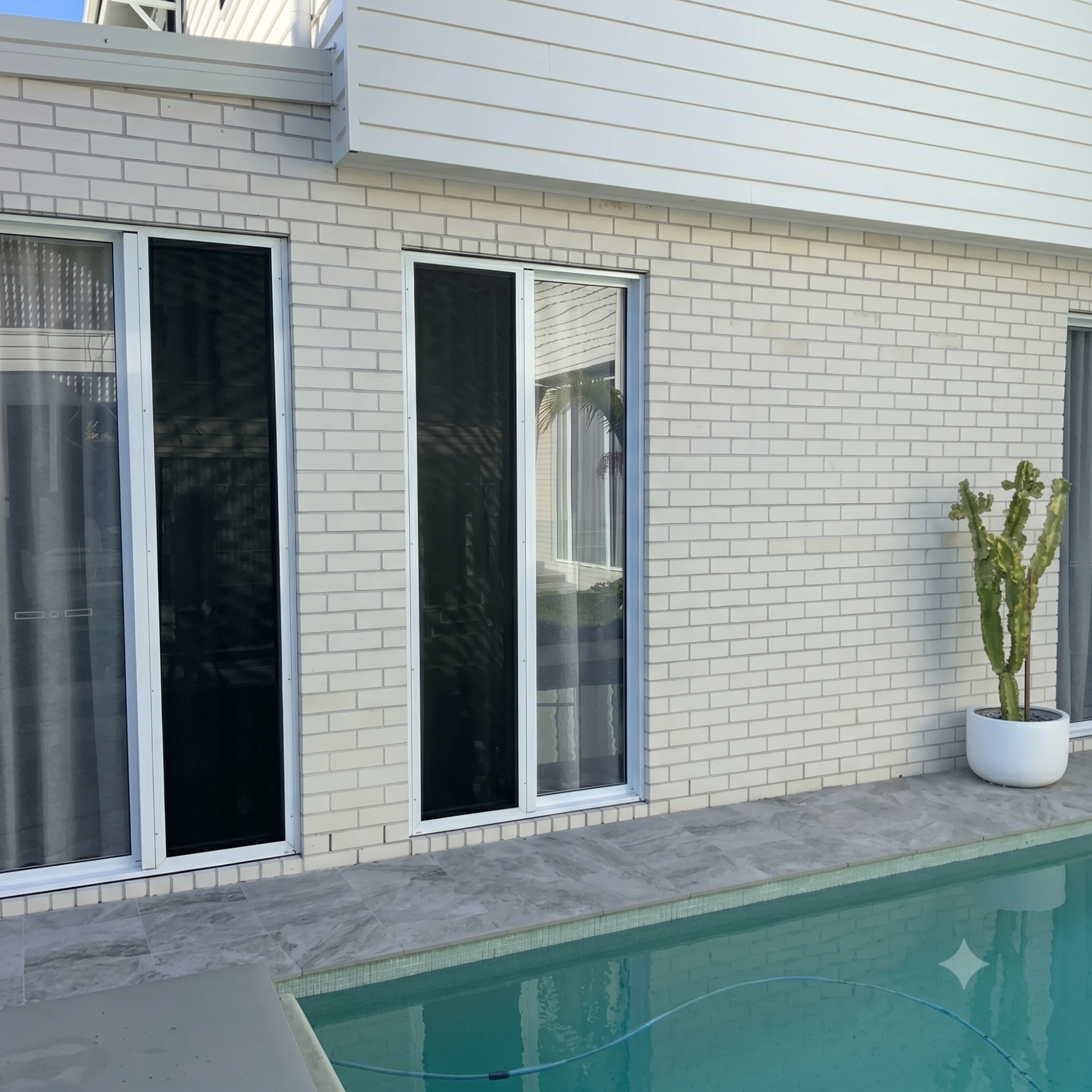 White-framed window security screens on a Gold Coast poolside home by Gold Coast Blinds and Shutters