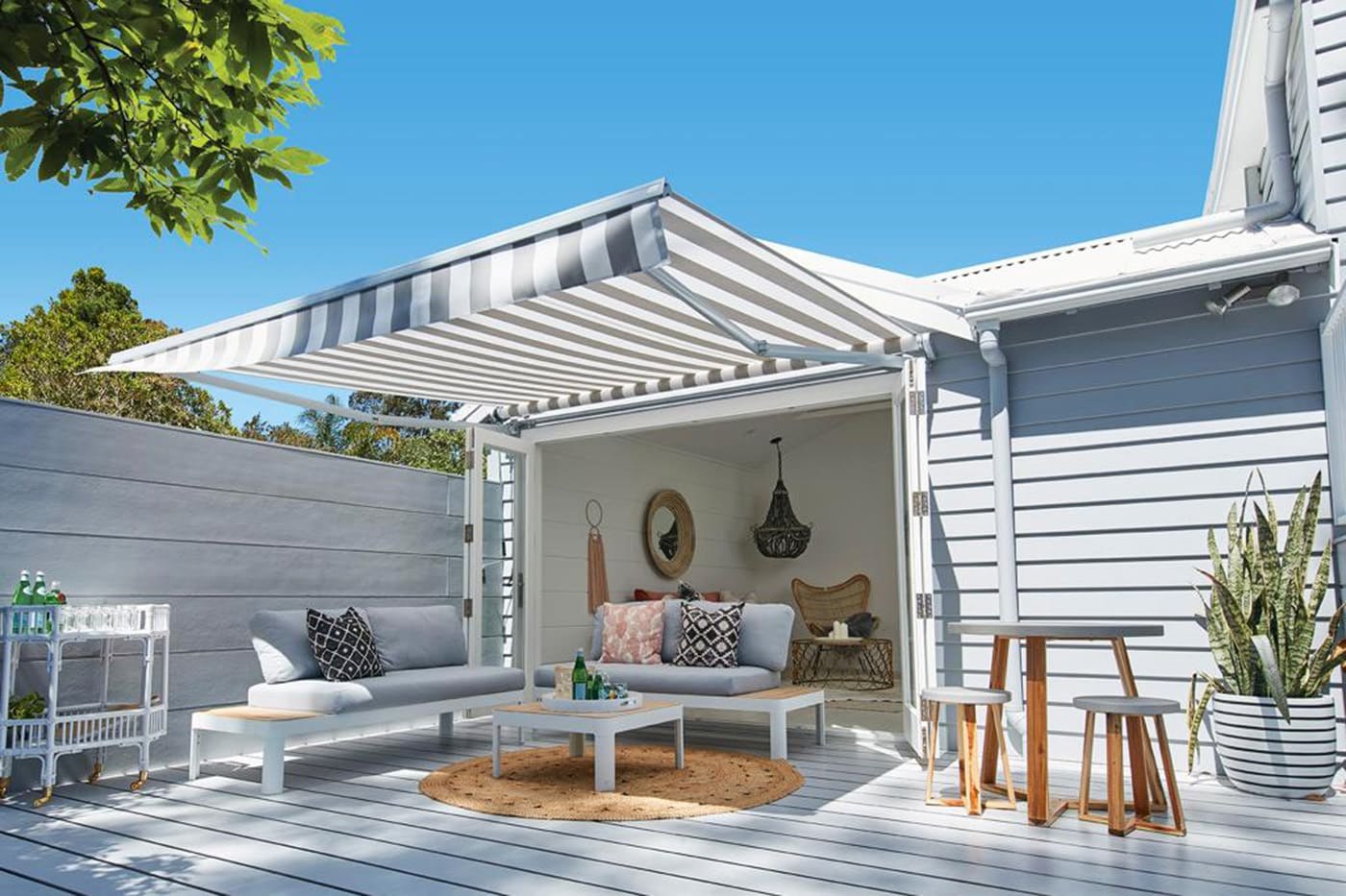 Striped retractable awning extended over a coastal outdoor lounge and entertaining deck on the Gold Coast