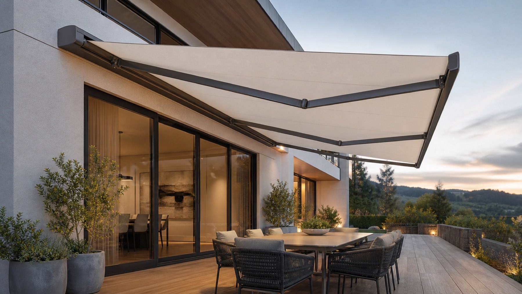 Modern retractable folding-arm awning extended over an alfresco dining deck at dusk