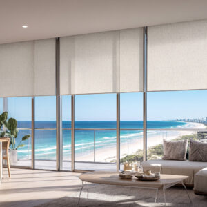 Cream sunscreen roller blinds half-lowered across floor-to-ceiling glass in a Gold Coast oceanview apartment
