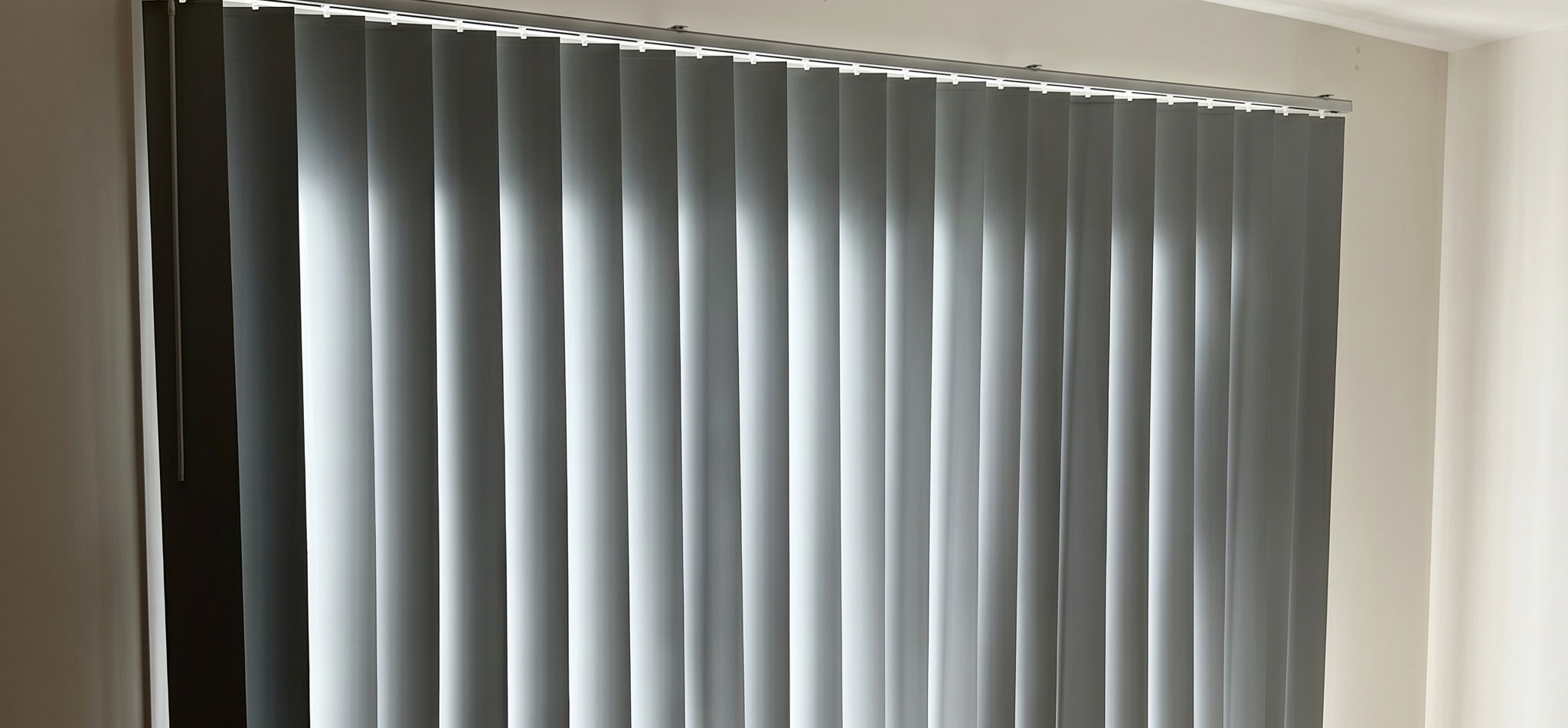 Vertical blinds stacked to one side of a sliding door opening